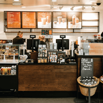 Menu board and till area of a newly remodeled Starbucks restaurant. Two employees are preparing drinks behind the counter.