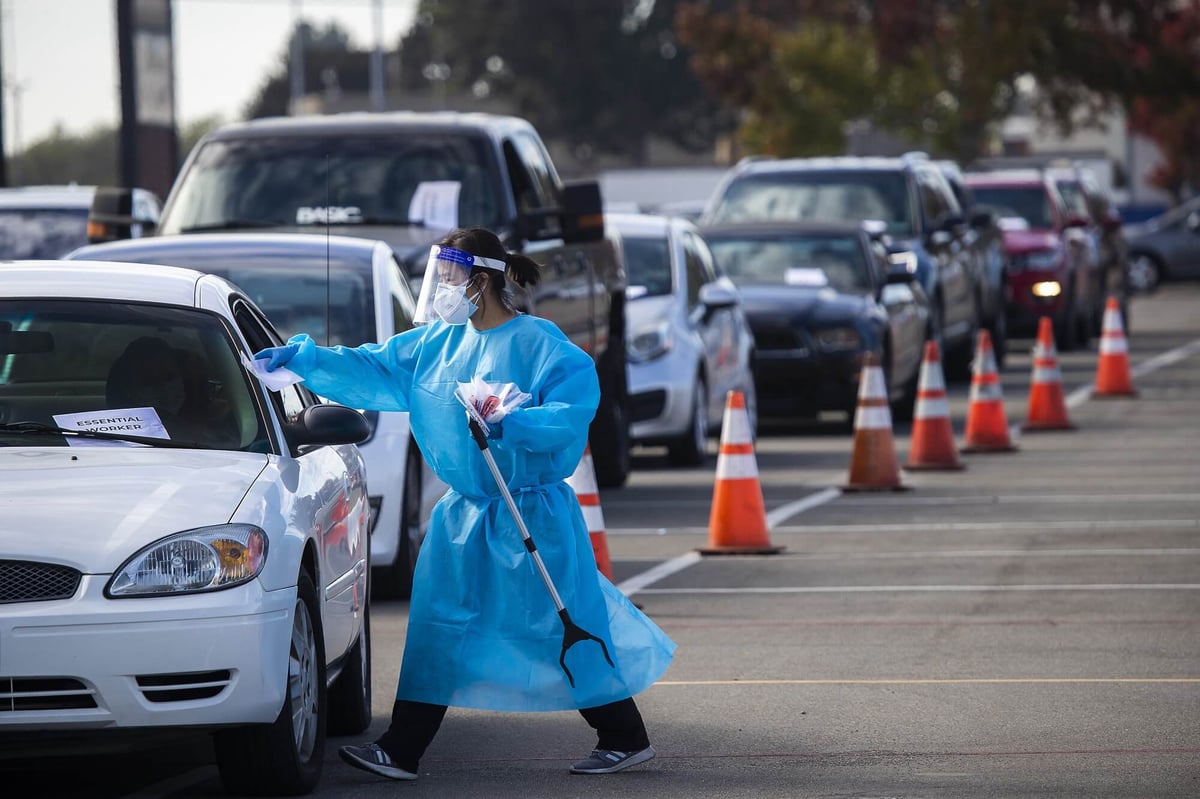 DAVACO employee in a protective face mask, shield and protective wear testing car driver for Covid-19 in Texas.