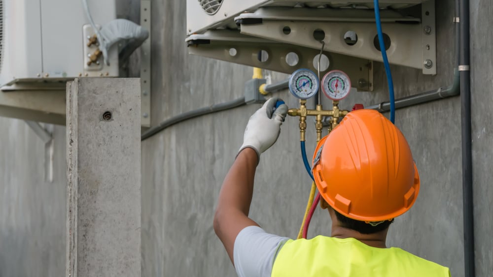 Man in hard hat working on HVAC unit