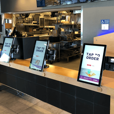 Front counter of a Taco Bell restaurant, featuring colorful LCD touch screens for customer self-service, allowing for faster order pickup.