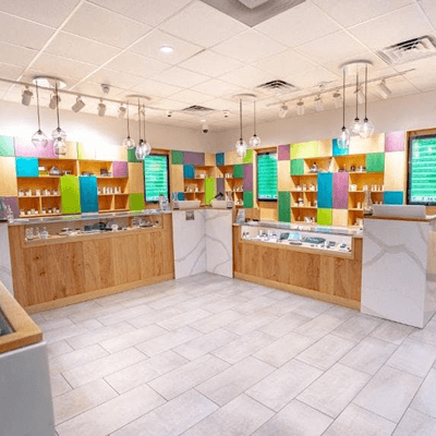 Interior view of a Trulieve cannabis store. White marble accents match the white and grey flooring with wooden accents and colorful, block artwork.