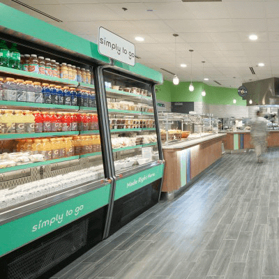 Bright green open refrigerators stocked with colorful beverages and prepared deli items at the US Air Force dining facility.