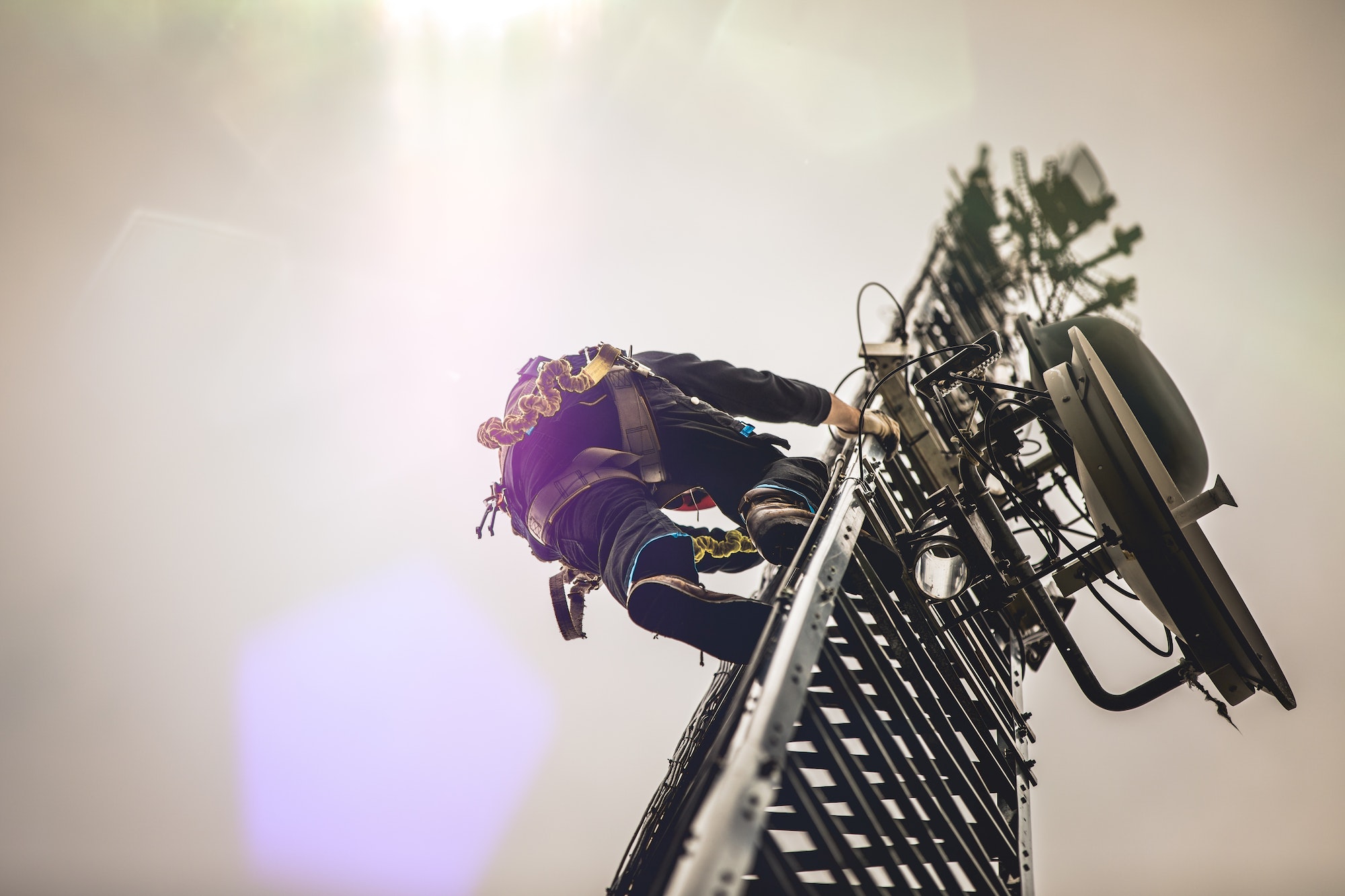 Telecom Worker Climbing Antenna Tower with Harness and Tools